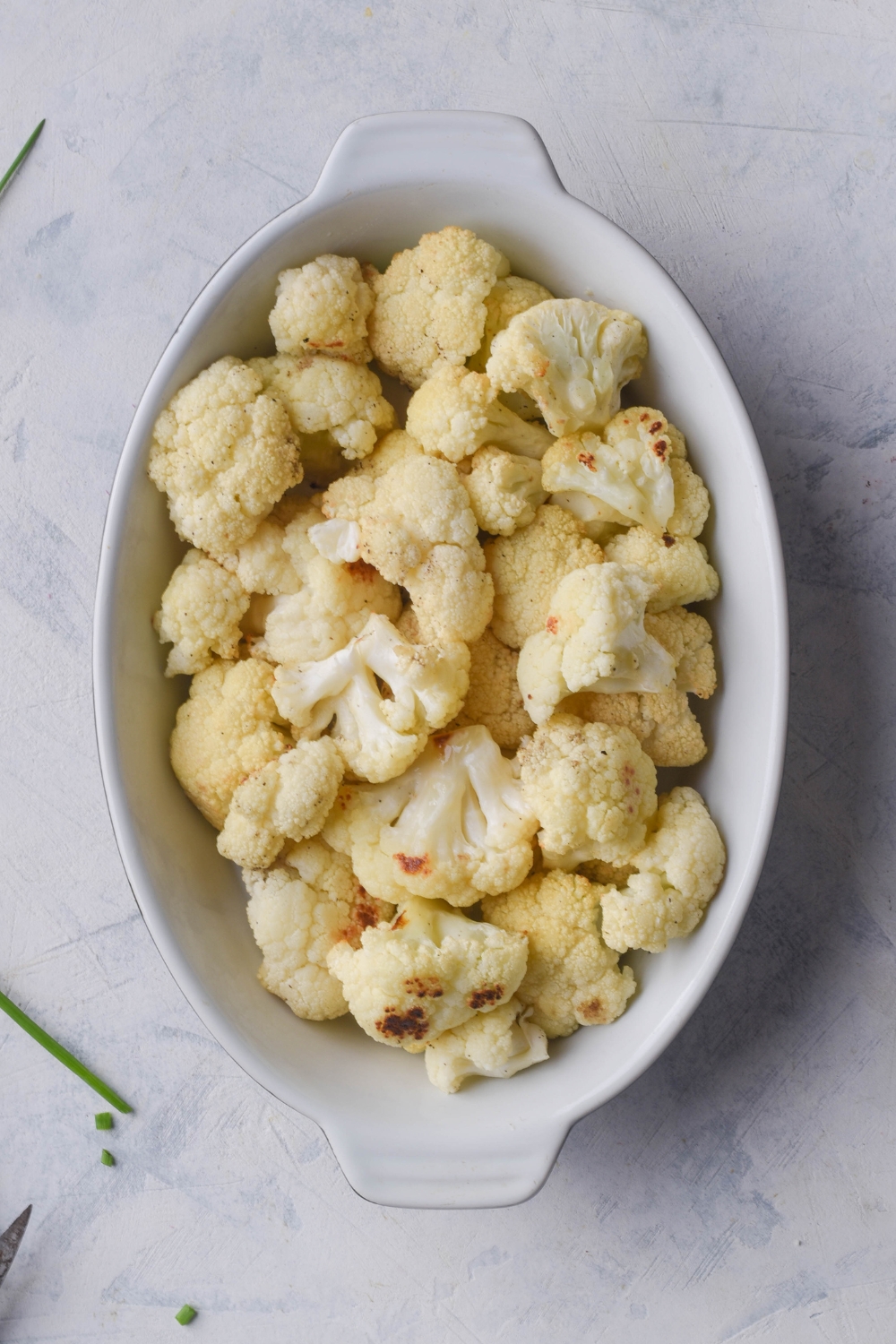 An overhead view of a baking dish with roasted cauliflower florets in it.