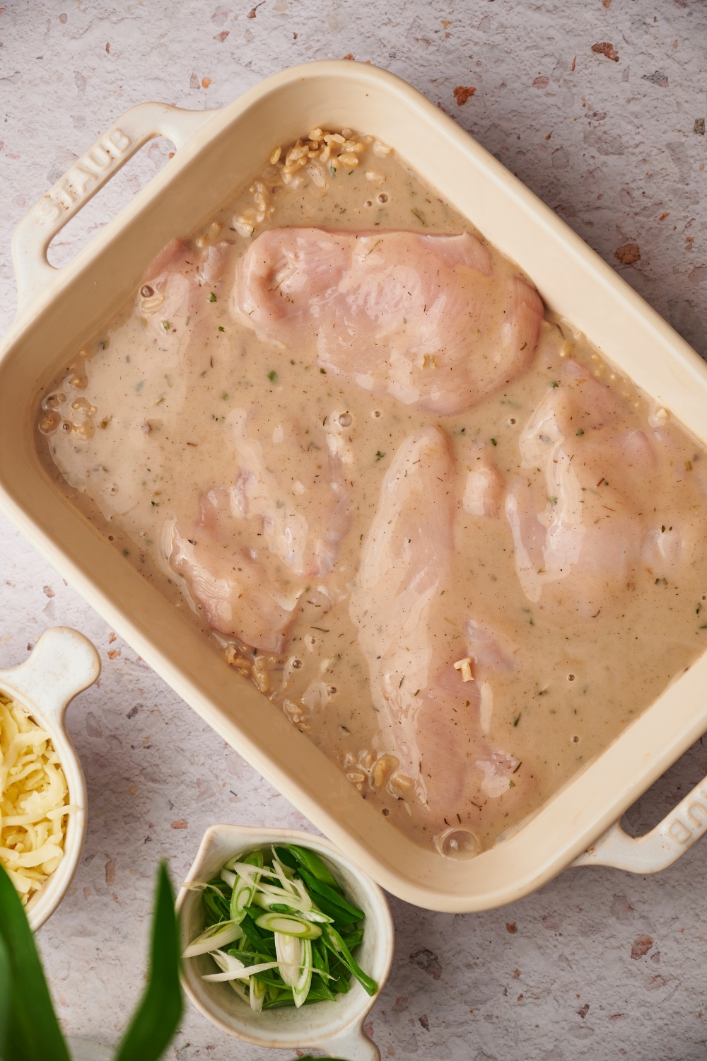 An overhead view of a casserole dish with uncooked chicken casserole in it.