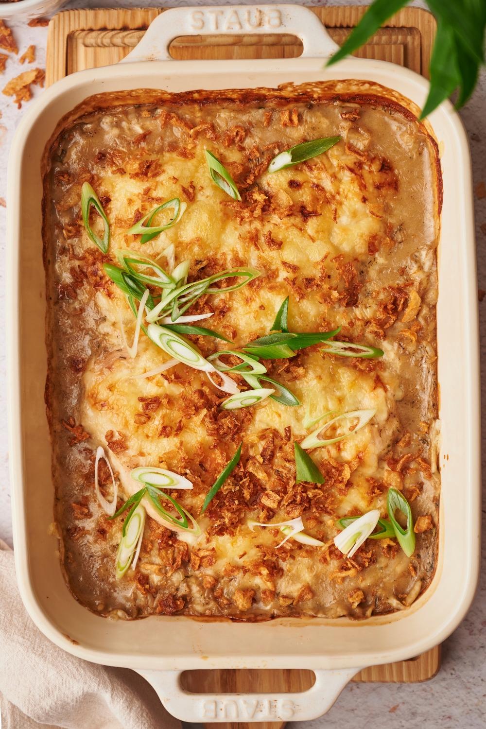 An overhead view of baked chicken casserole talked with green onions.