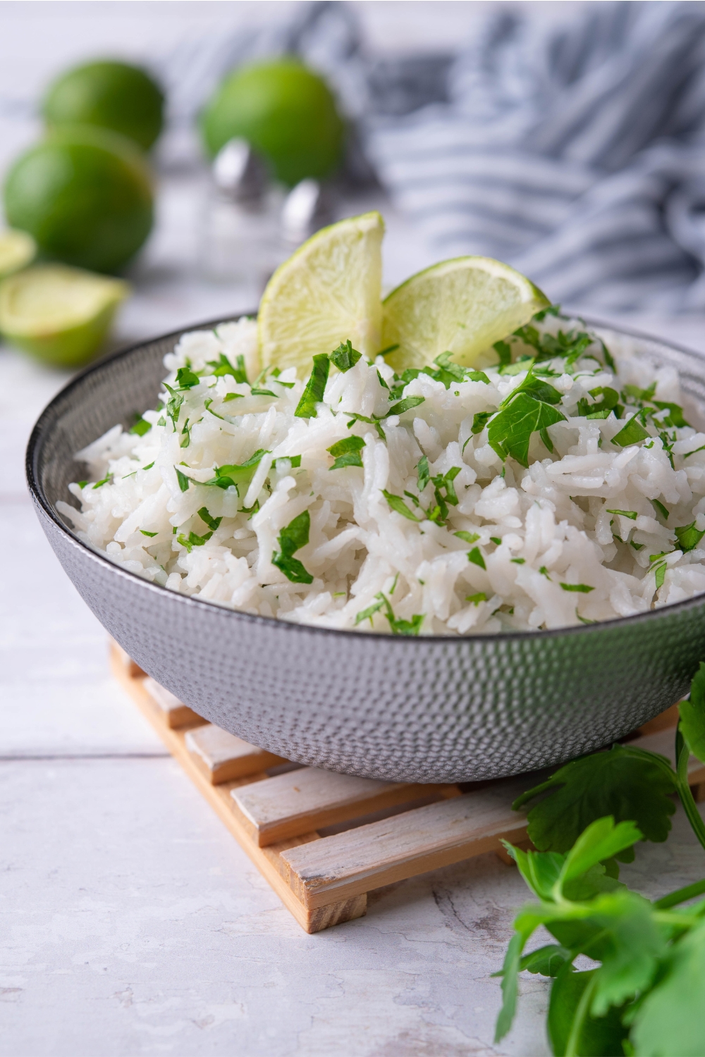 Two limes and chopped cilantro on top of white rice that is in a bowl.