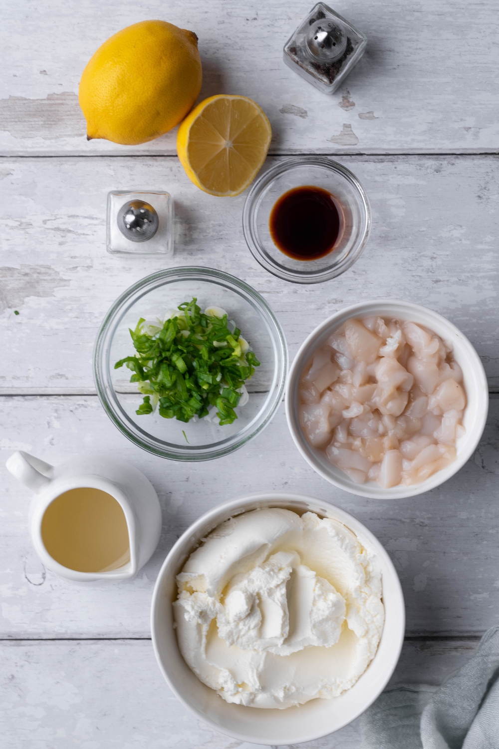A countertop with a bowl of cream cheese, clams, green onions, lemon juice, salt and pepper, and worcestershire sauce.
