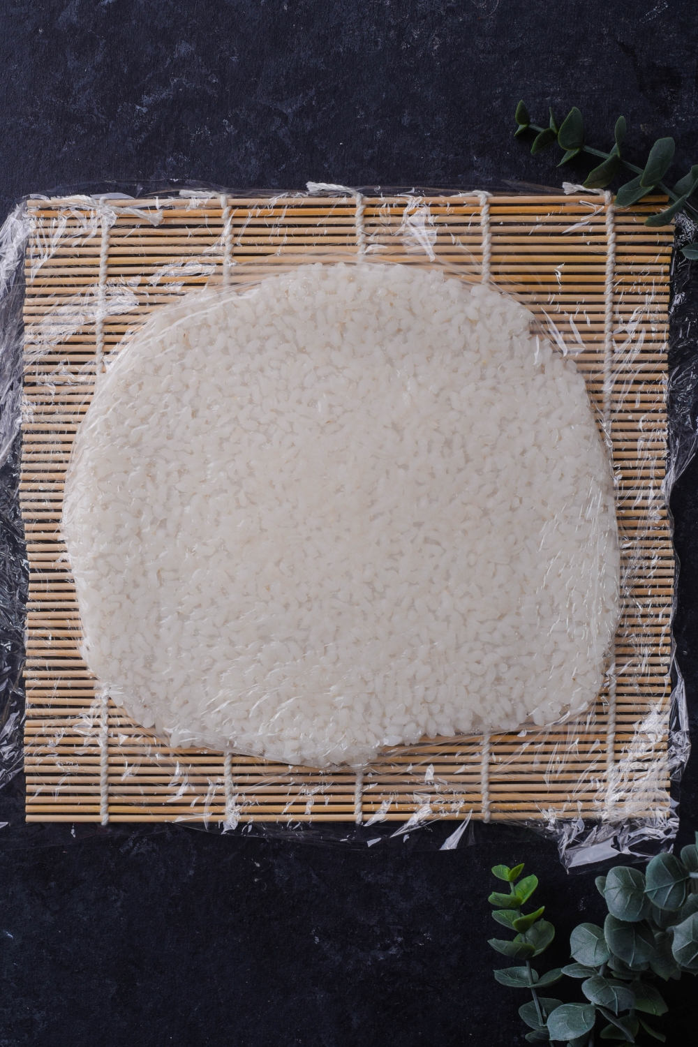 An overhead view of layer of sushi rice on a bamboo mat.