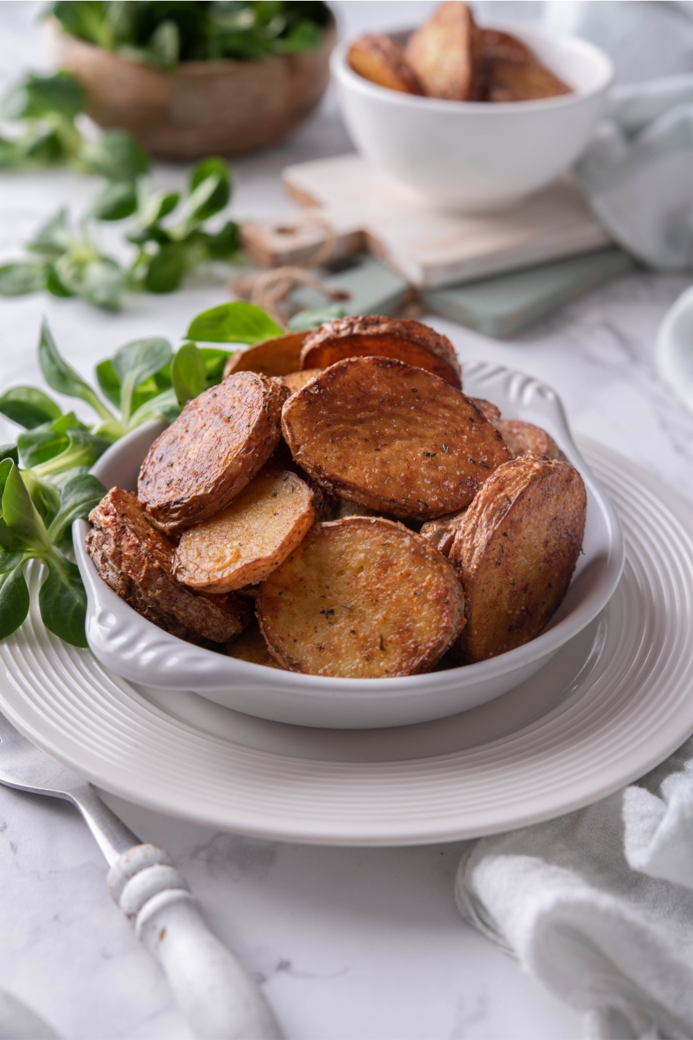 A serving dish with fried potatoes in it.
