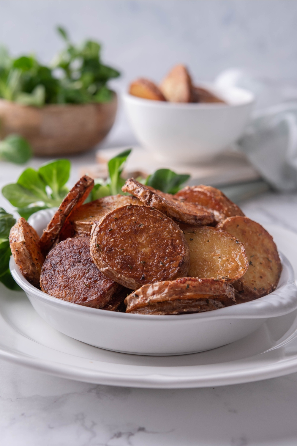 A serving dish with fried potatoes in it.