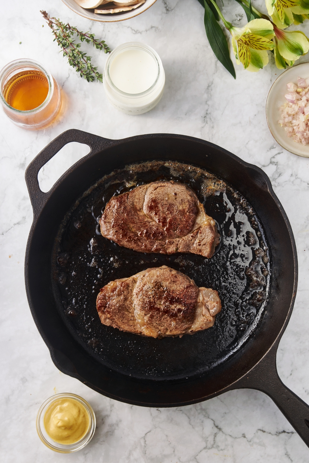 Two seared filet mignon steaks in a cast iron skillet with melted butter.