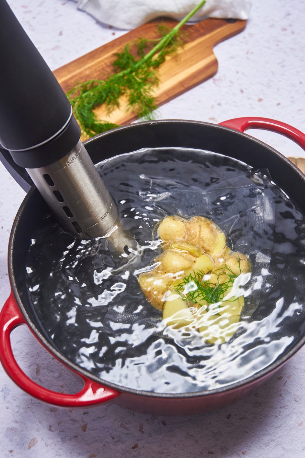 Potatoes in a sealed sous vide bag being sous vide in a large pot of water.