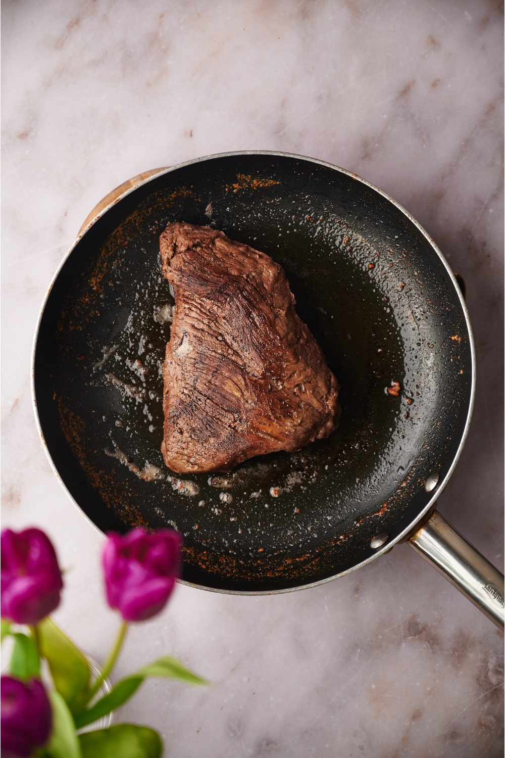 A seared steak in a black skillet.