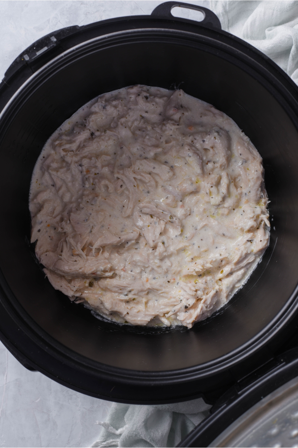 A slow cooker with cooked chicken in a cream sauce.