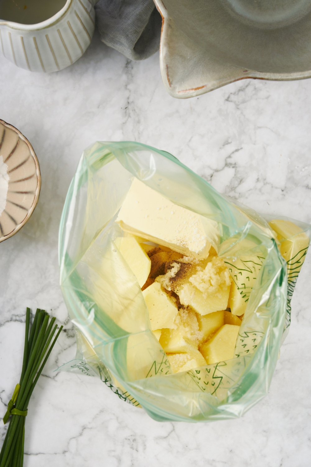 A Ziploc bag with diced and peeled potatoes, a large tab of butter, and spices in the bag.