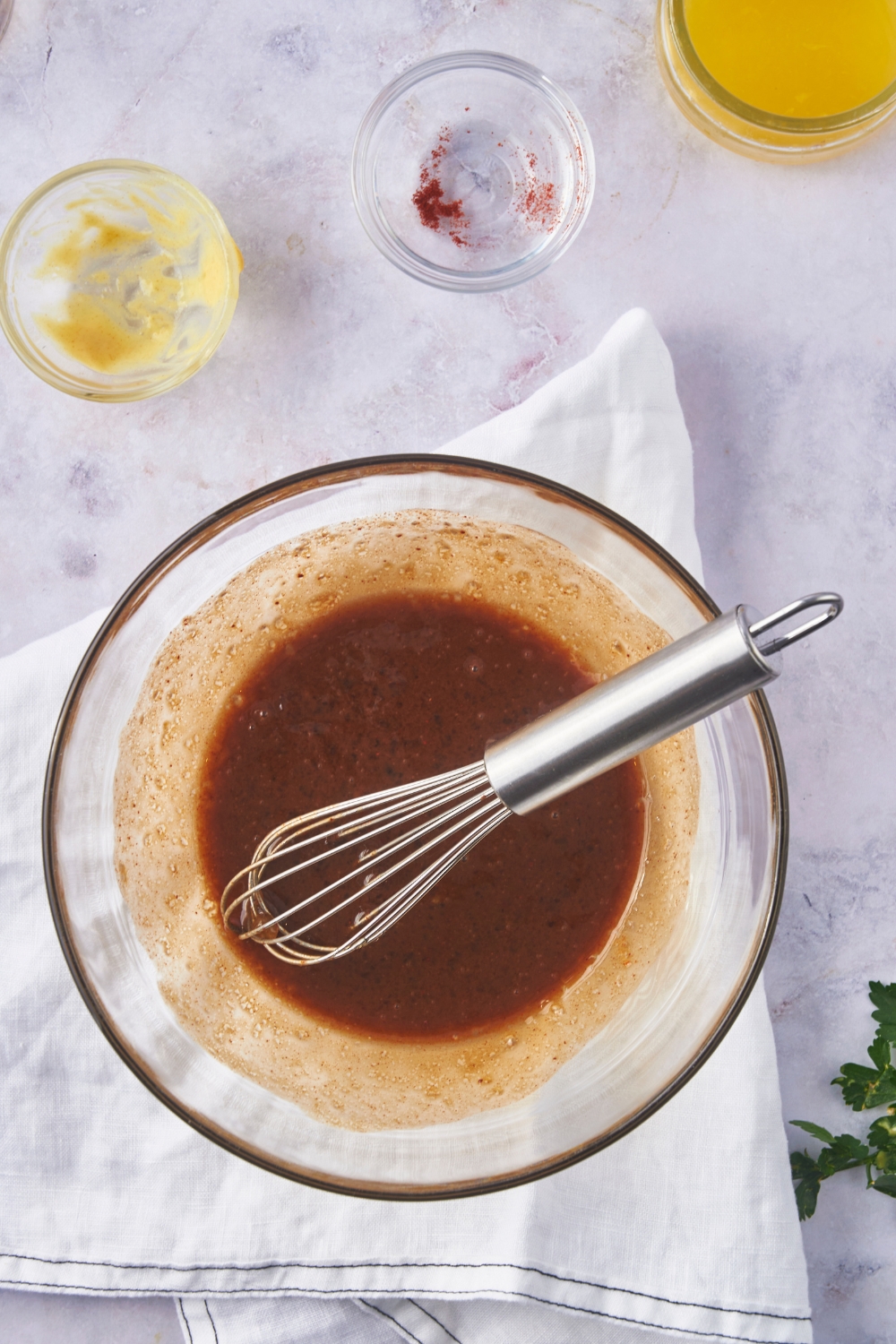 A clear bowl filled with a brown sauce mixture and a whisk is in the bowl.