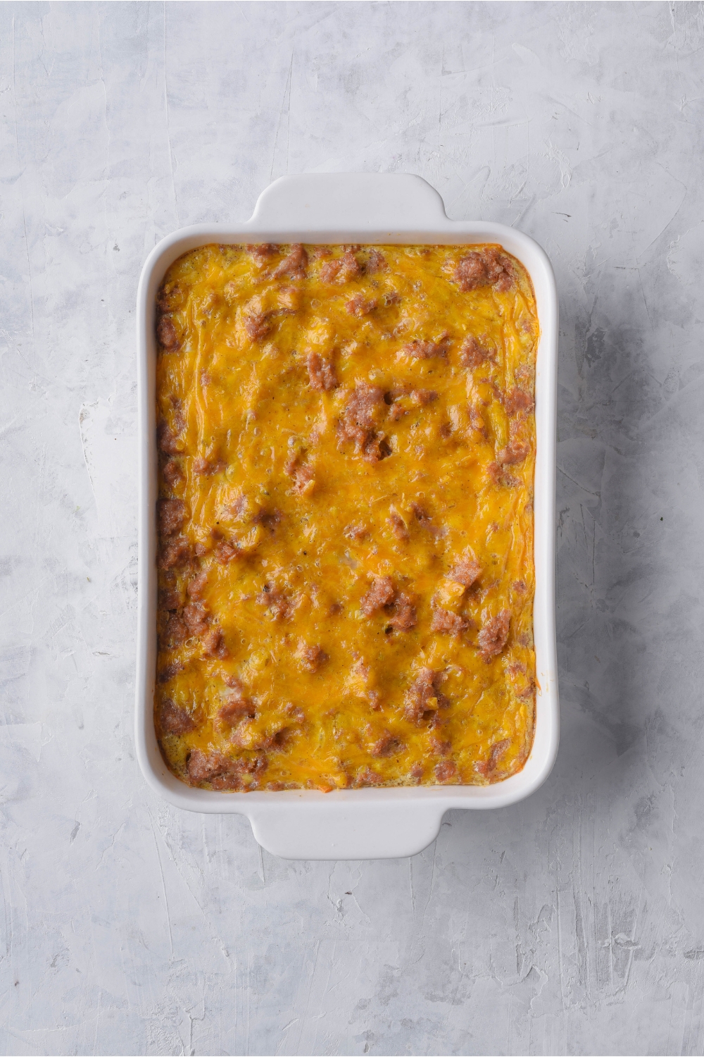 Overhead view of a cooked breakfast casserole in a white baking dish.