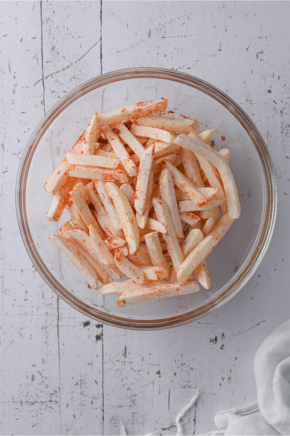 A clear bowl filled with seasoned frozen french fries.