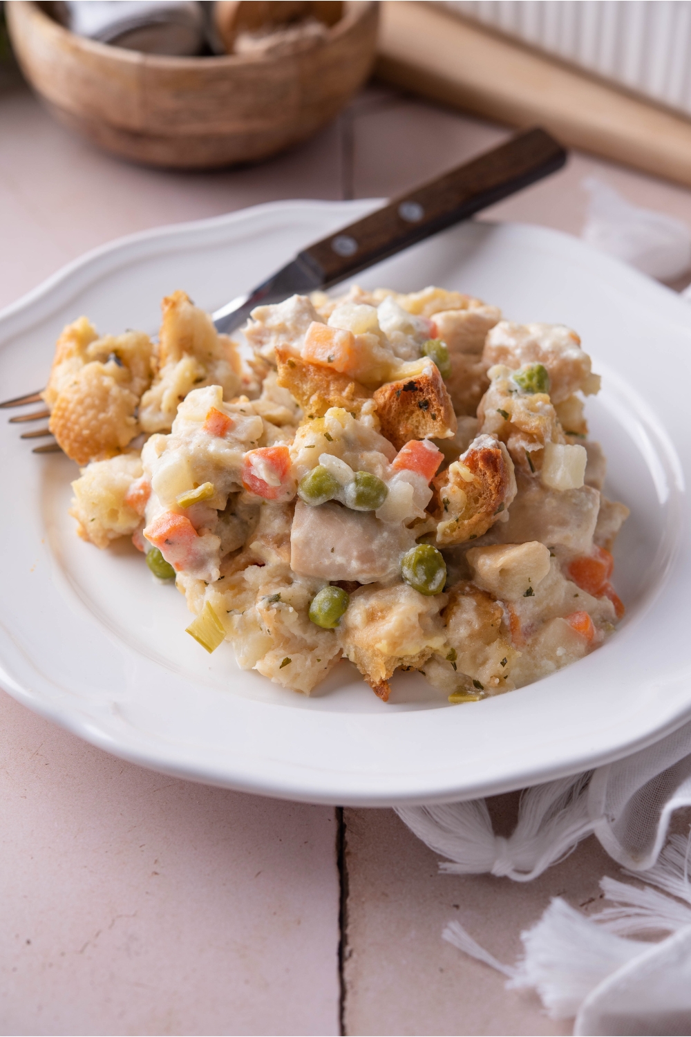 Chicken and stuffing casserole piled on a white plate with a fork on the plate.