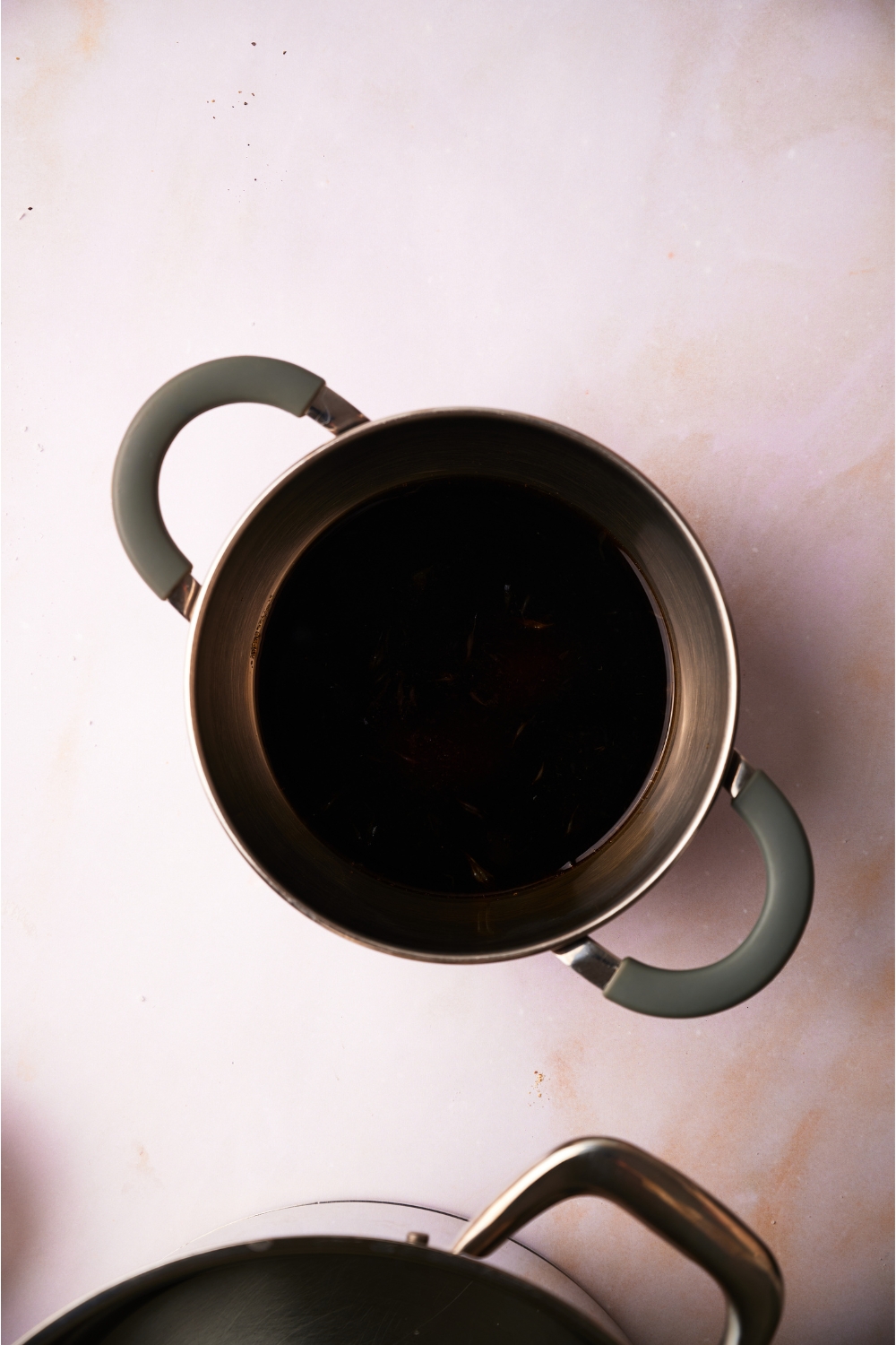 A small sauce pot with soy sauce in it.