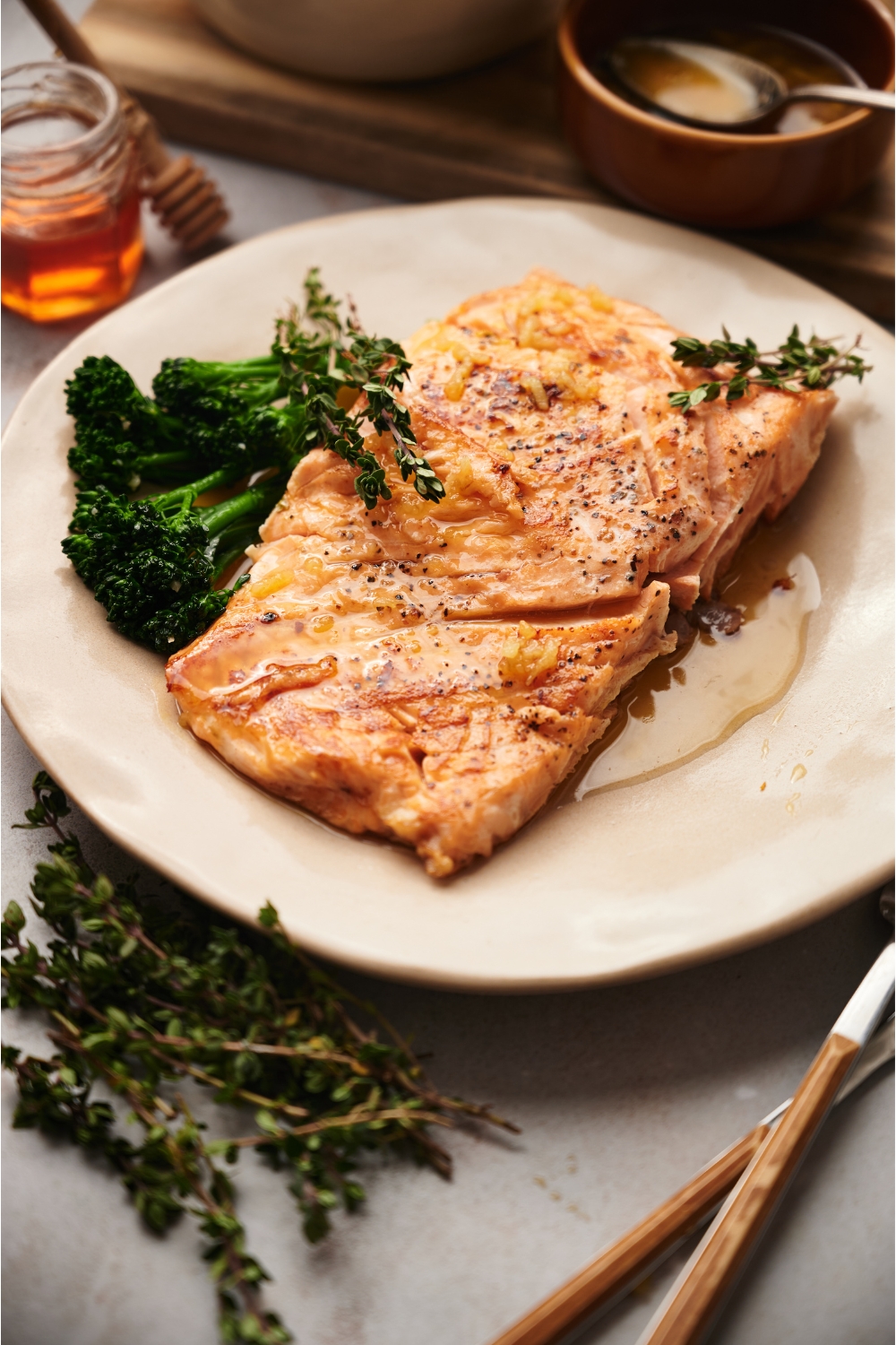 Sous vide salmon on an orange plate with a side of broccolini and a sauce poured overtop the salmon.