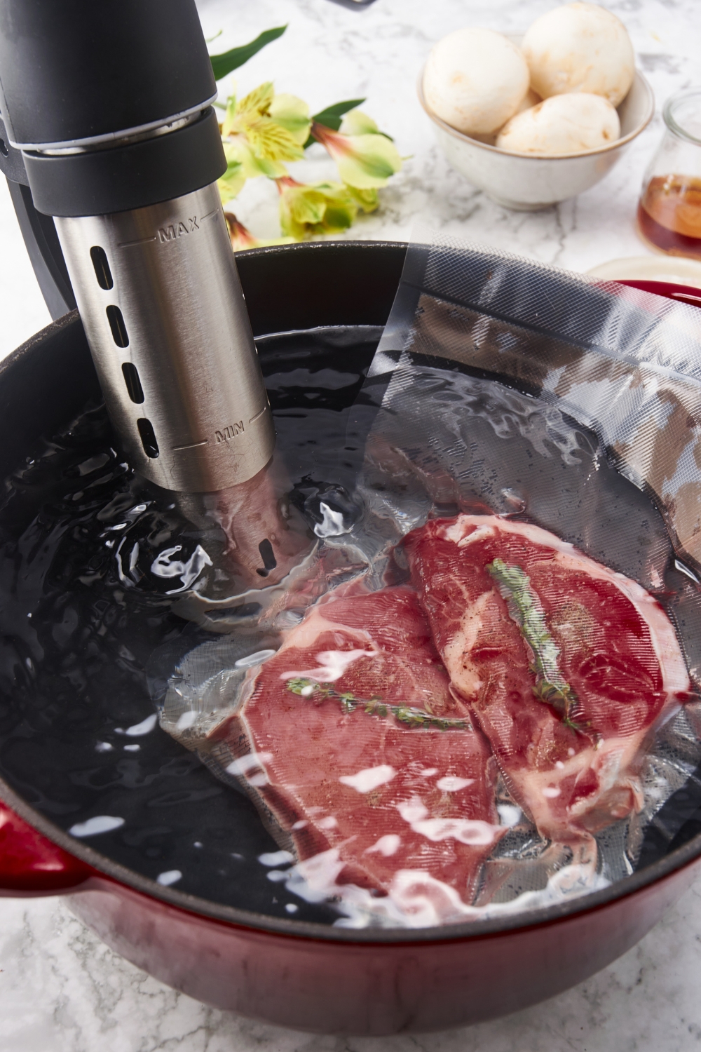 Two filet mignon steaks being sous vide in a large water bath.