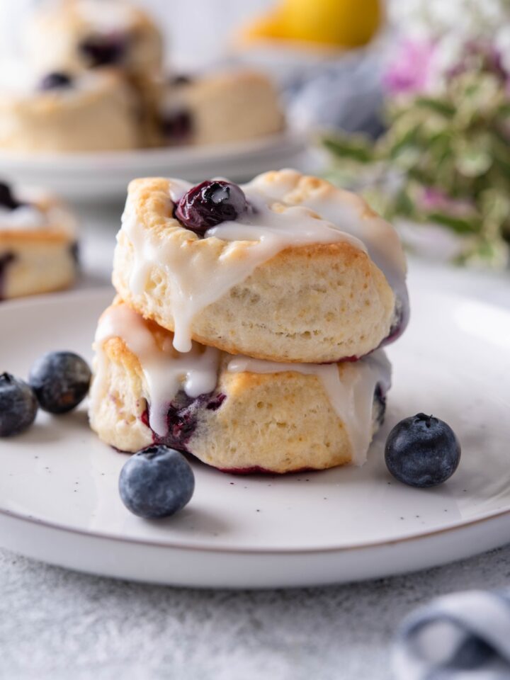 A stack of two blueberry biscuits topped with icing on a plate.