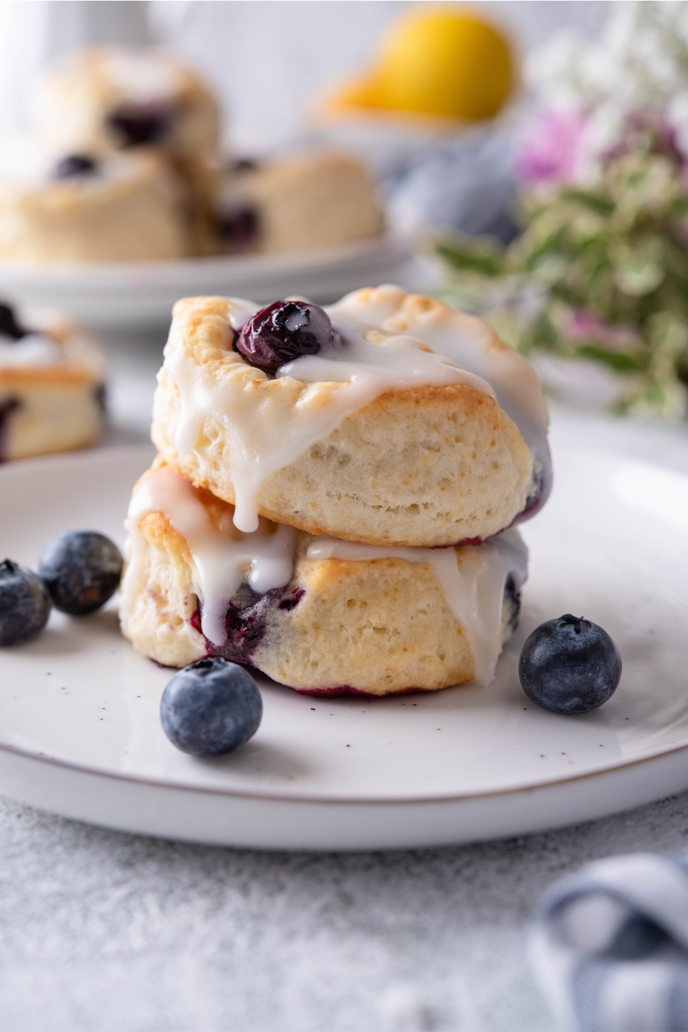 A stack of two blueberry biscuits topped with icing on a plate.