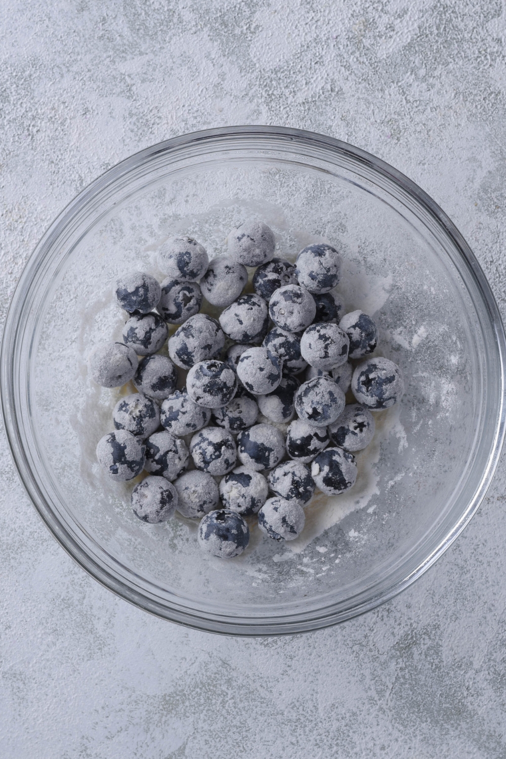 A mixing bowl with fresh blueberries covered in flour.