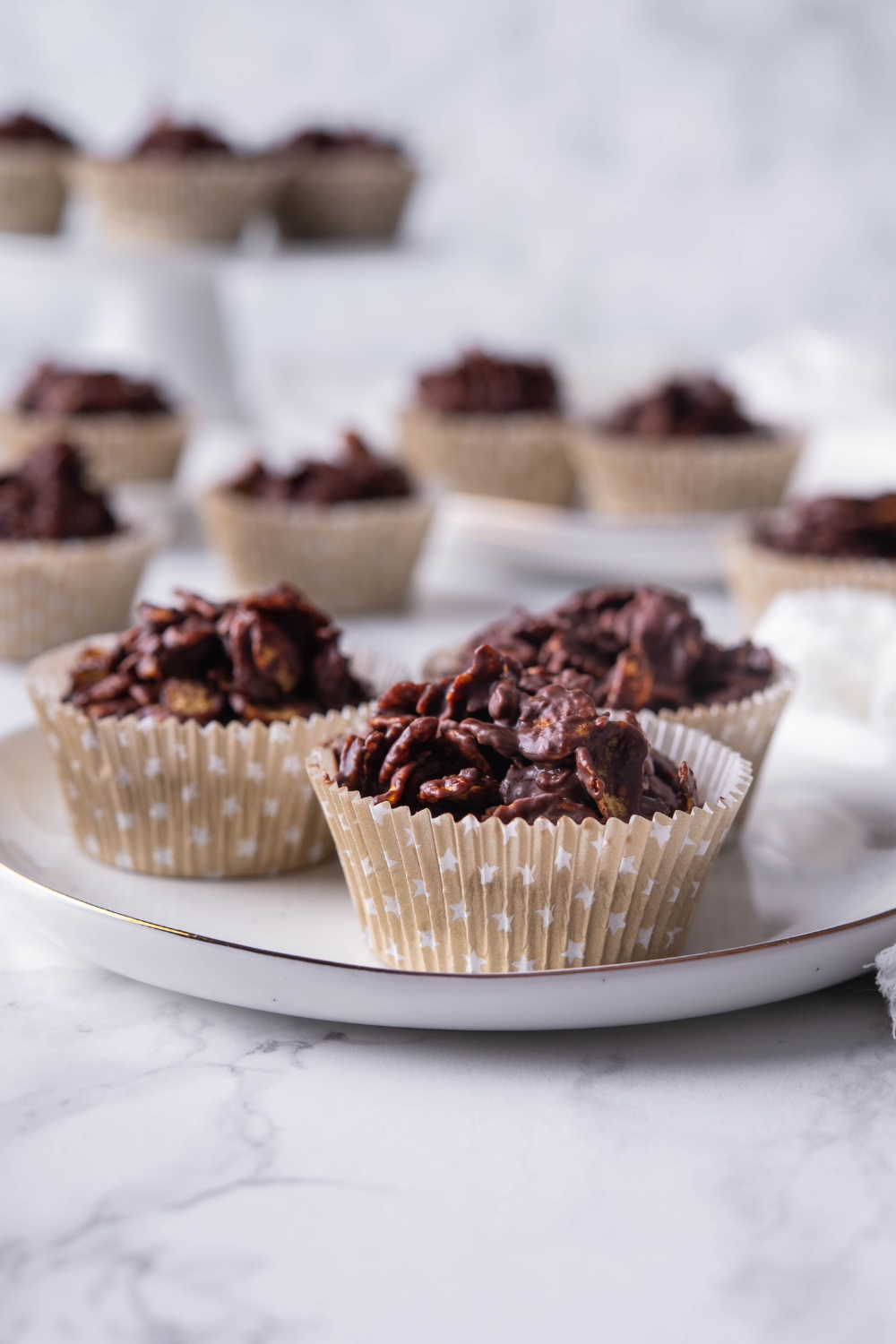 Chocolate cornflake clusters in muffin liners served on a plate.