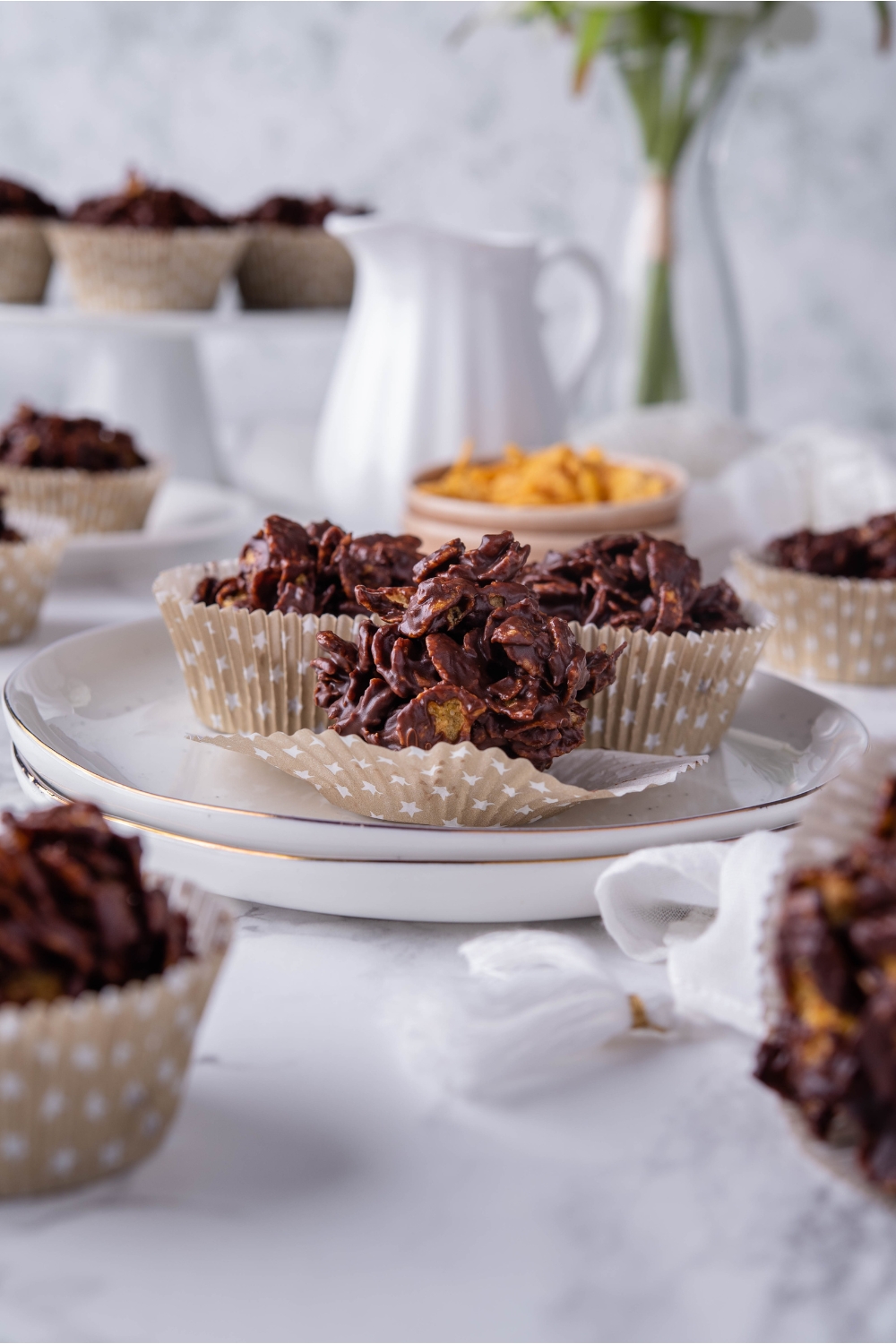 A plate with three chocolate cornflake clusters in muffin liners on a plate.