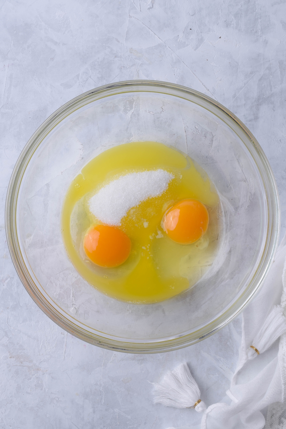 A mixing bowl with eggs and sugar.