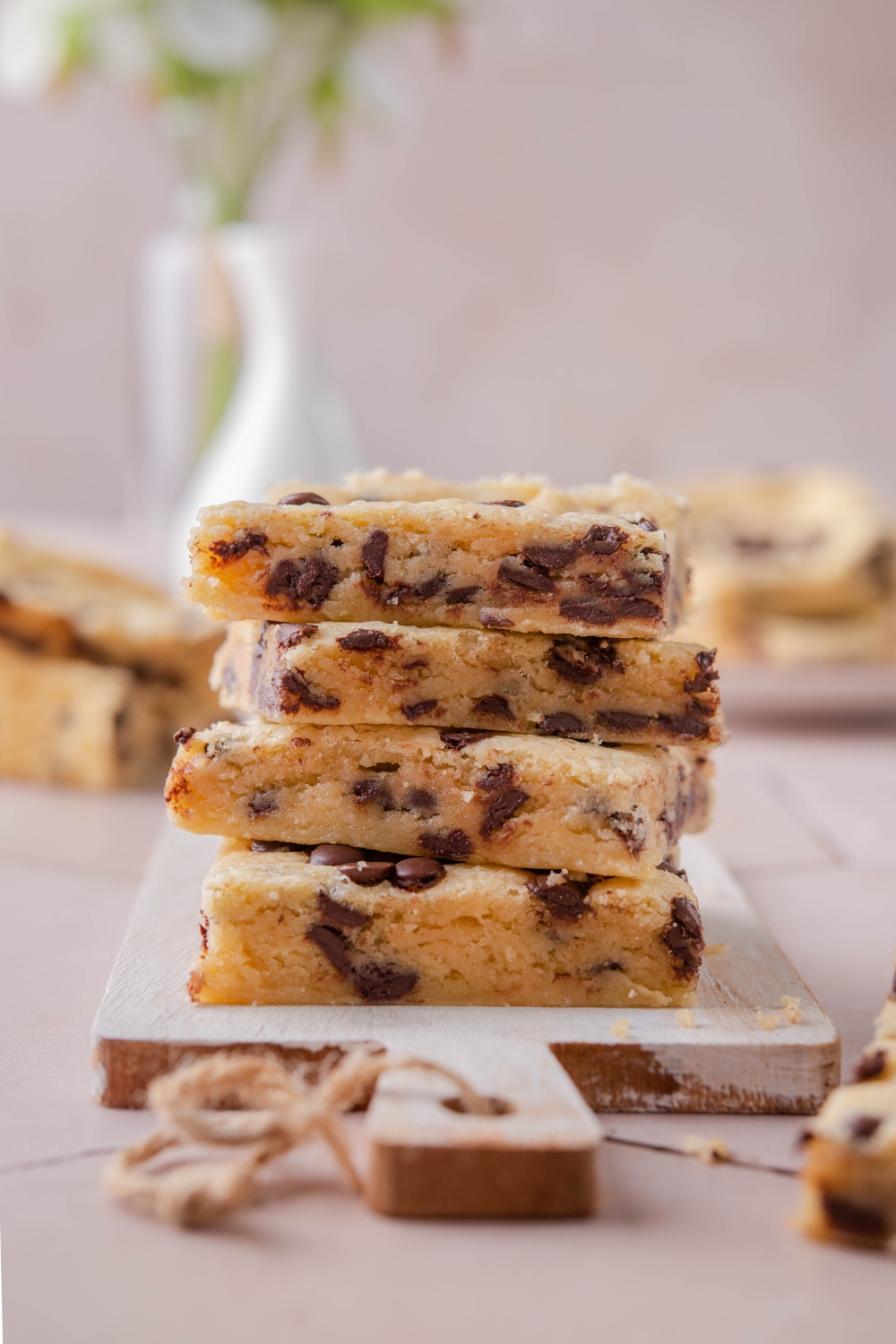 A stack of chocolate chip cookie bars on a wooden serving board.