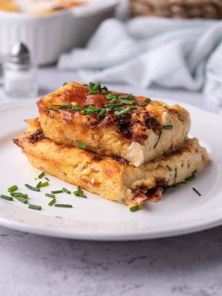 Two squares of twice baked potato casserole stacked on top of each other.