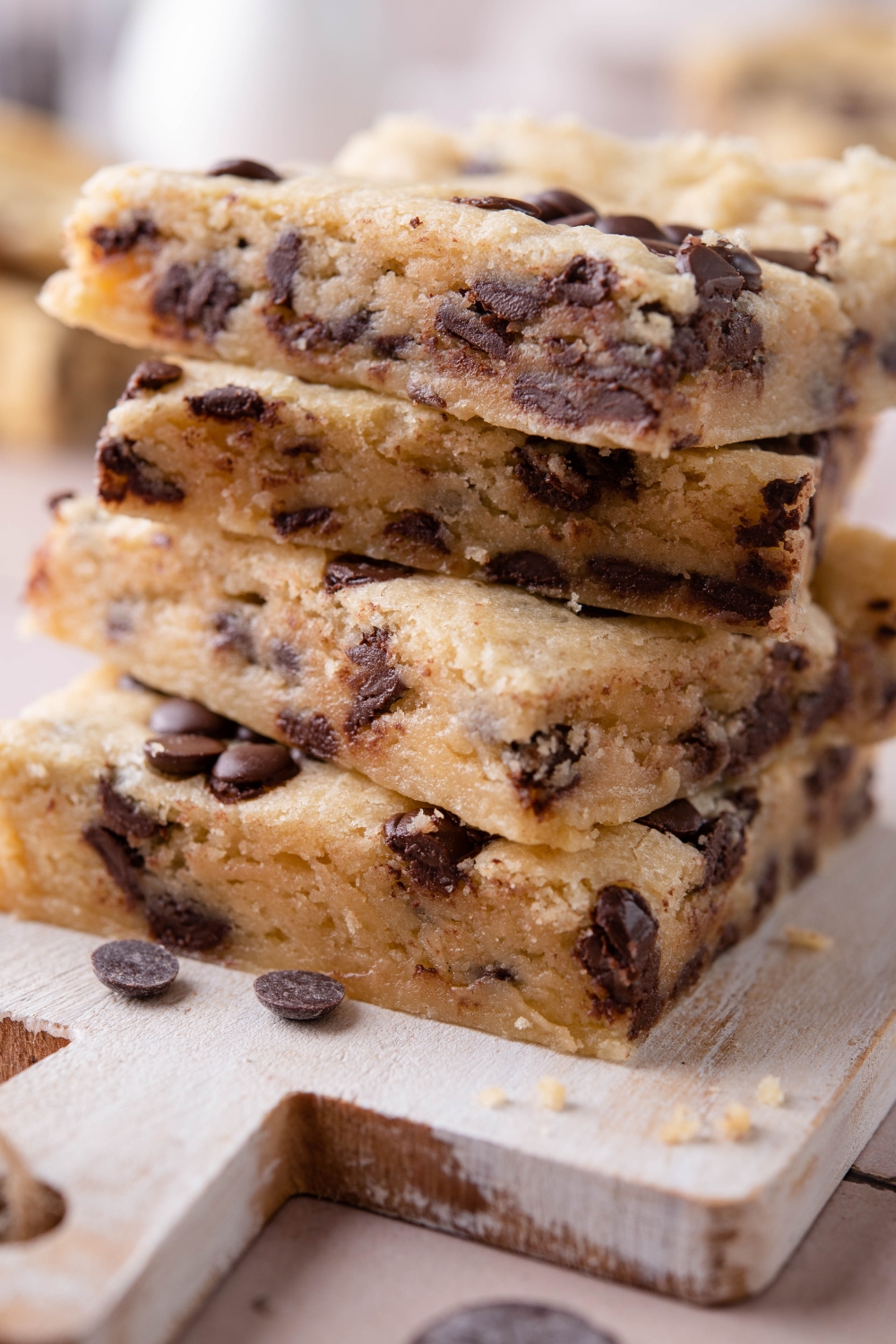 A close-up of a stack of chocolate chip cookie bars on a wooden serving board.