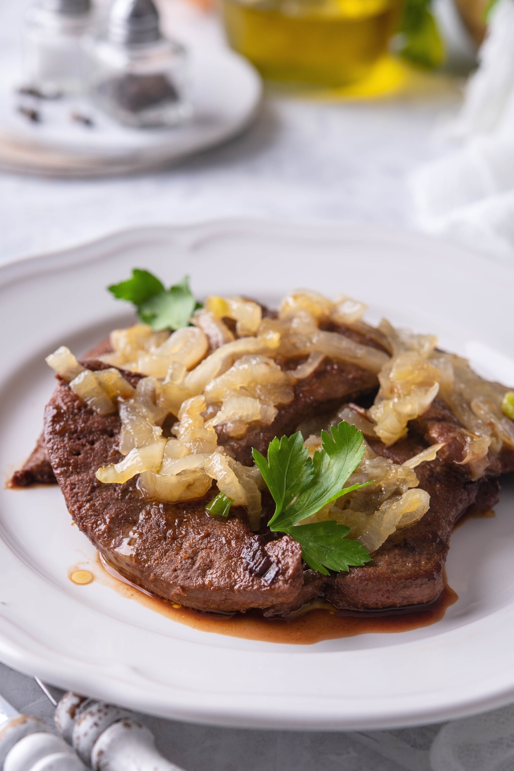 Chopped caramelized onions on top of liver on a plate.