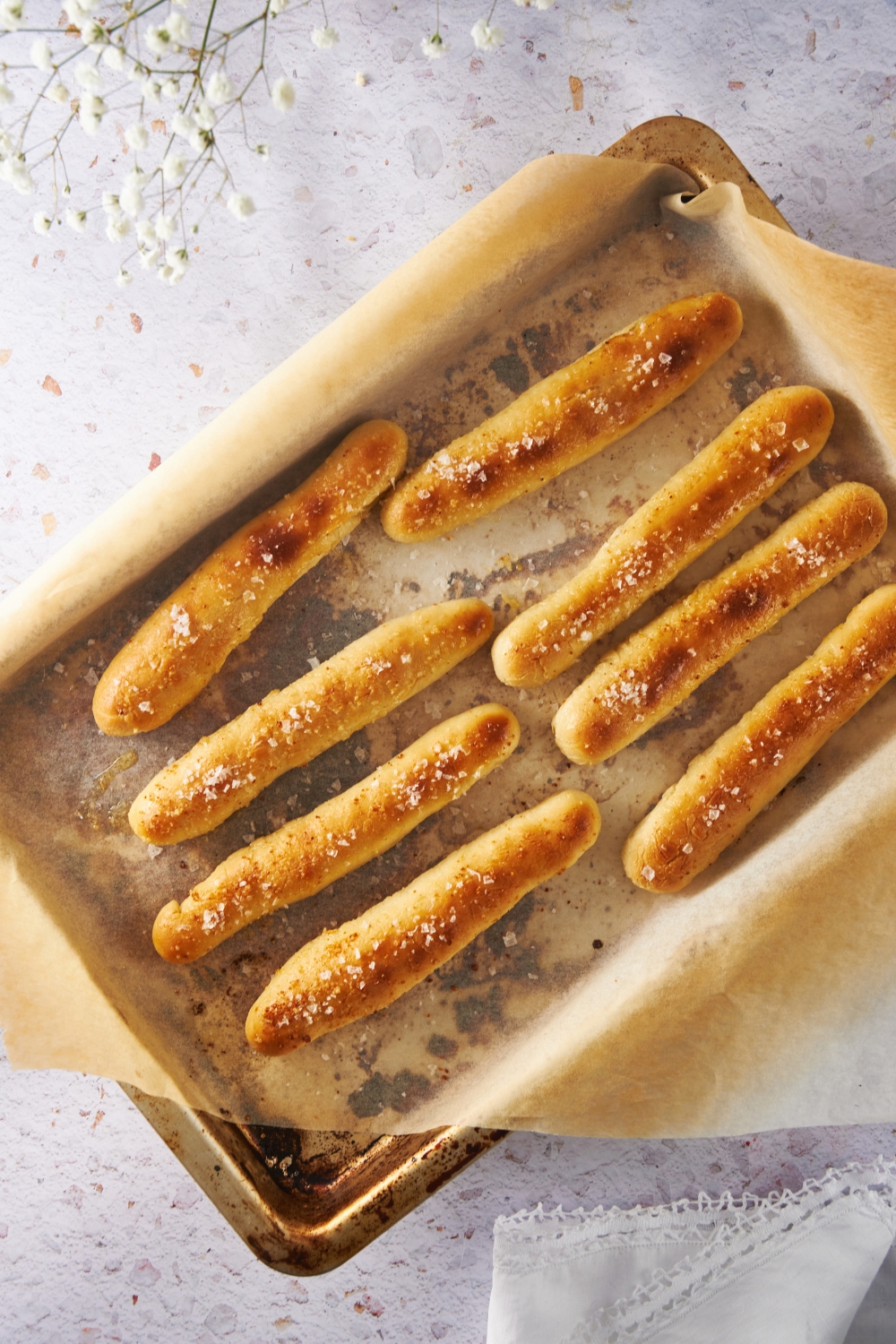 An overhead view of baked breadsticks on a baking sheet lined with parchment paper.