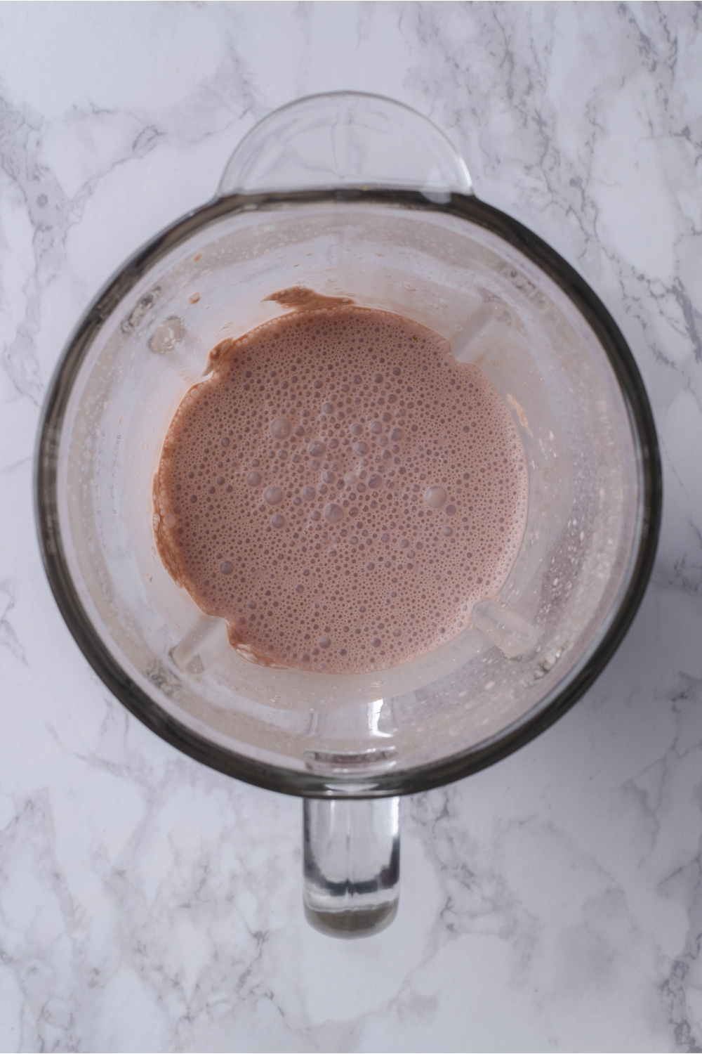 Overhead view of a blender with a chocolate milk mixture in it.
