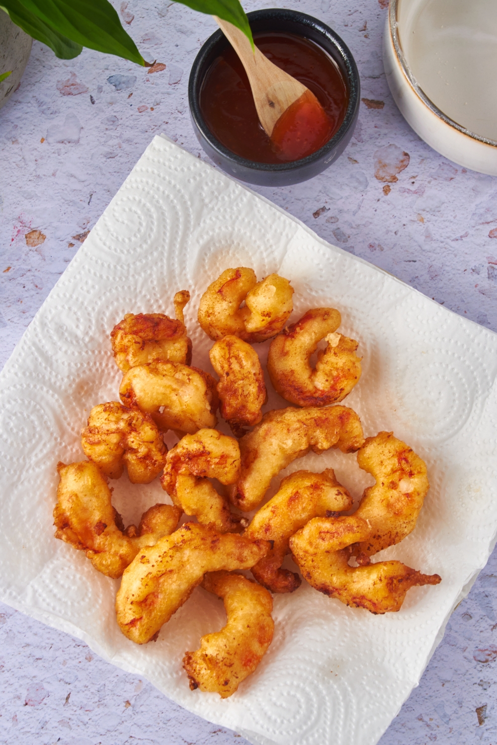 Overhead of a pile of fried shrimp on a plate lined with paper towels.