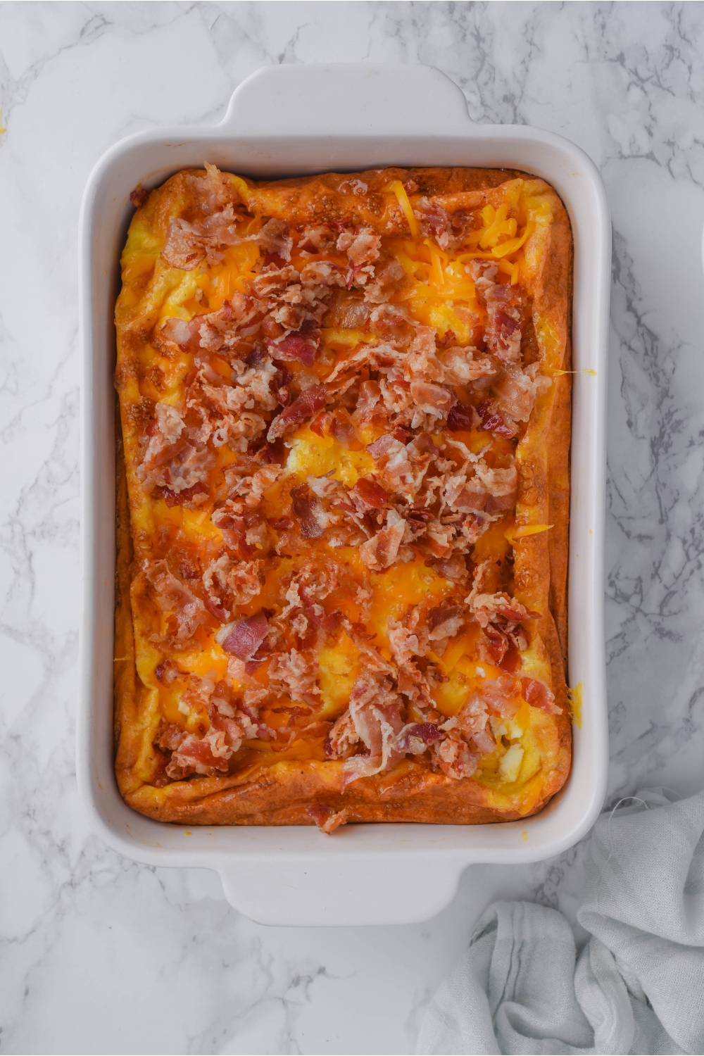 Overhead view of a breakfast casserole that has been topped with crumbled bacon.