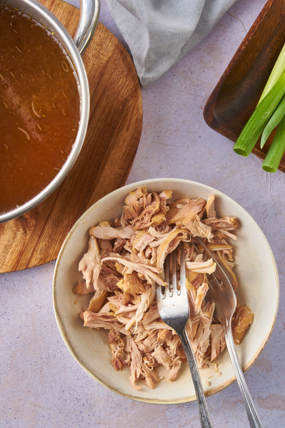 Bowl of cooked and shredded chicken with two forks in the bowl.