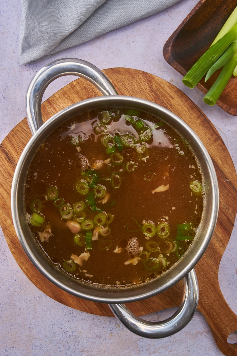 Pot filled with broth, garlic, ginger, and diced green onions.