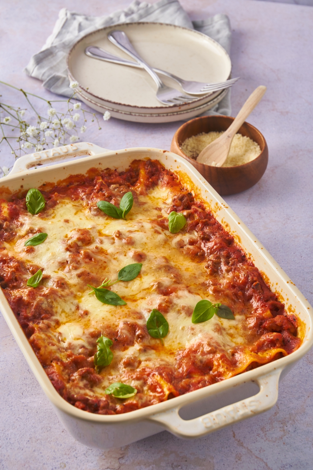 Baked lasagna covered in melted cheese and garnished with fresh basil.