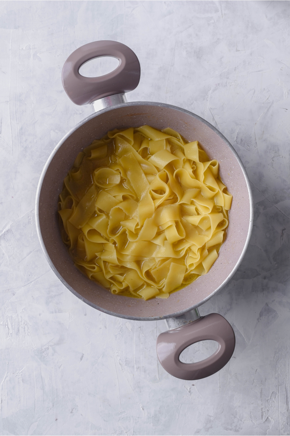 Grey pot filled with cooked egg noodles.