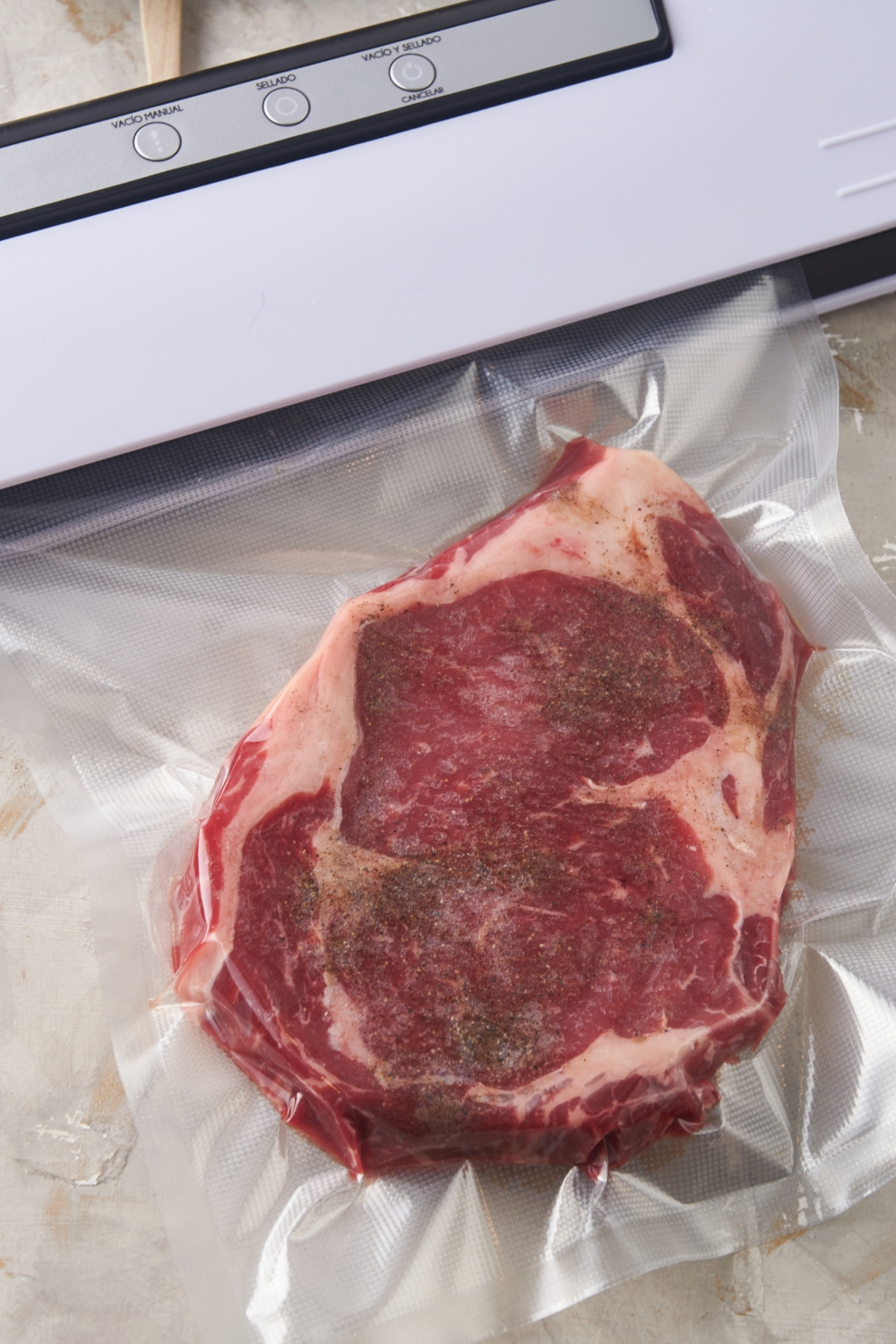 A seasoned ribeye steak in a vacuum sealed bag.