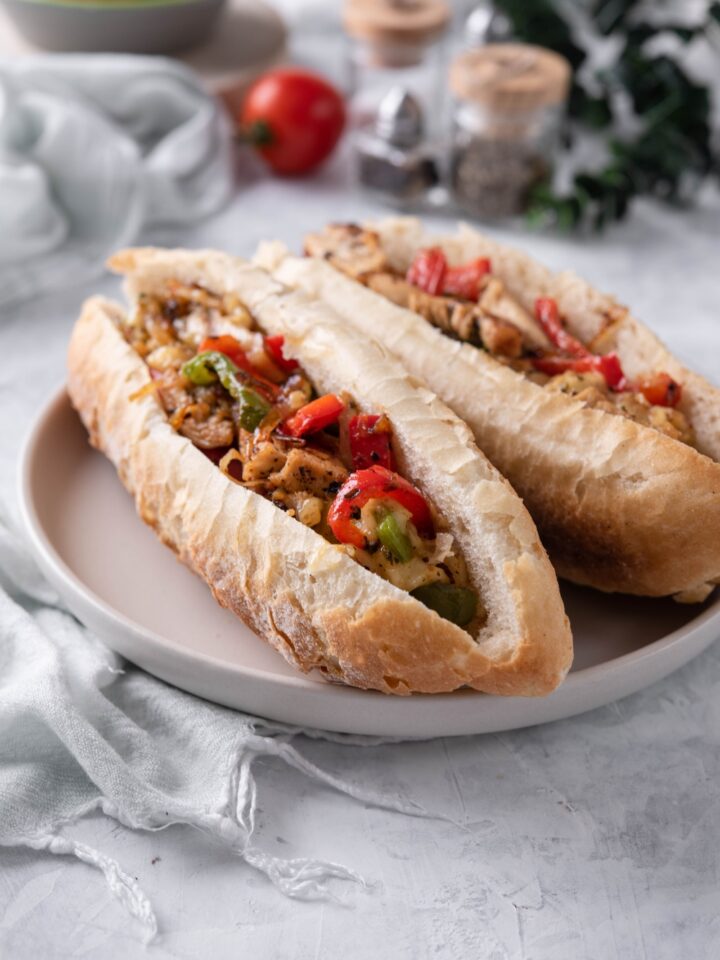 Two hoagie rolls sliced in half and stuffed with sautéed peppers, onions, and shredded chicken.