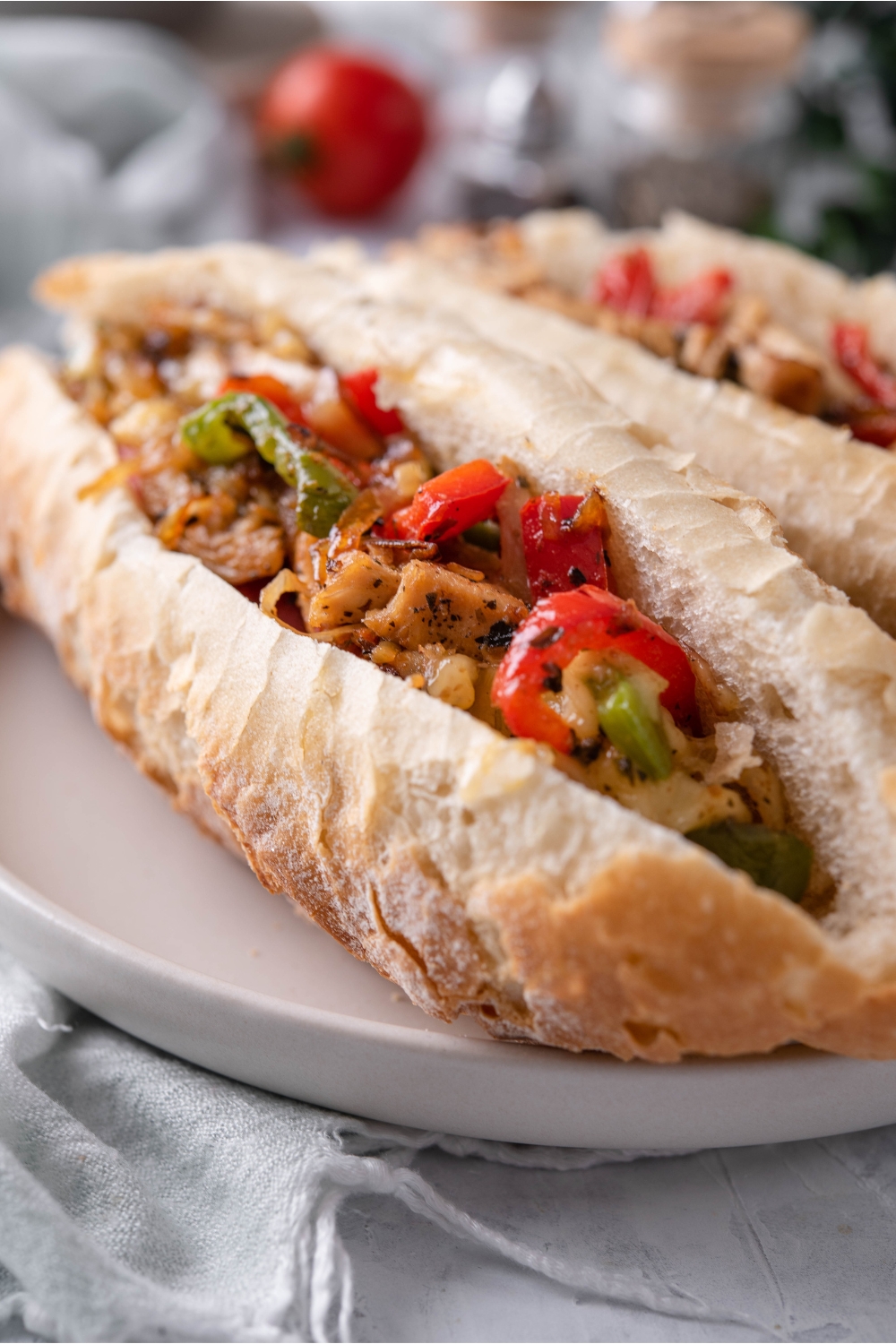 Close up of a hoagie roll sliced in half and stuffed with sautéed peppers, onions, and shredded chicken.