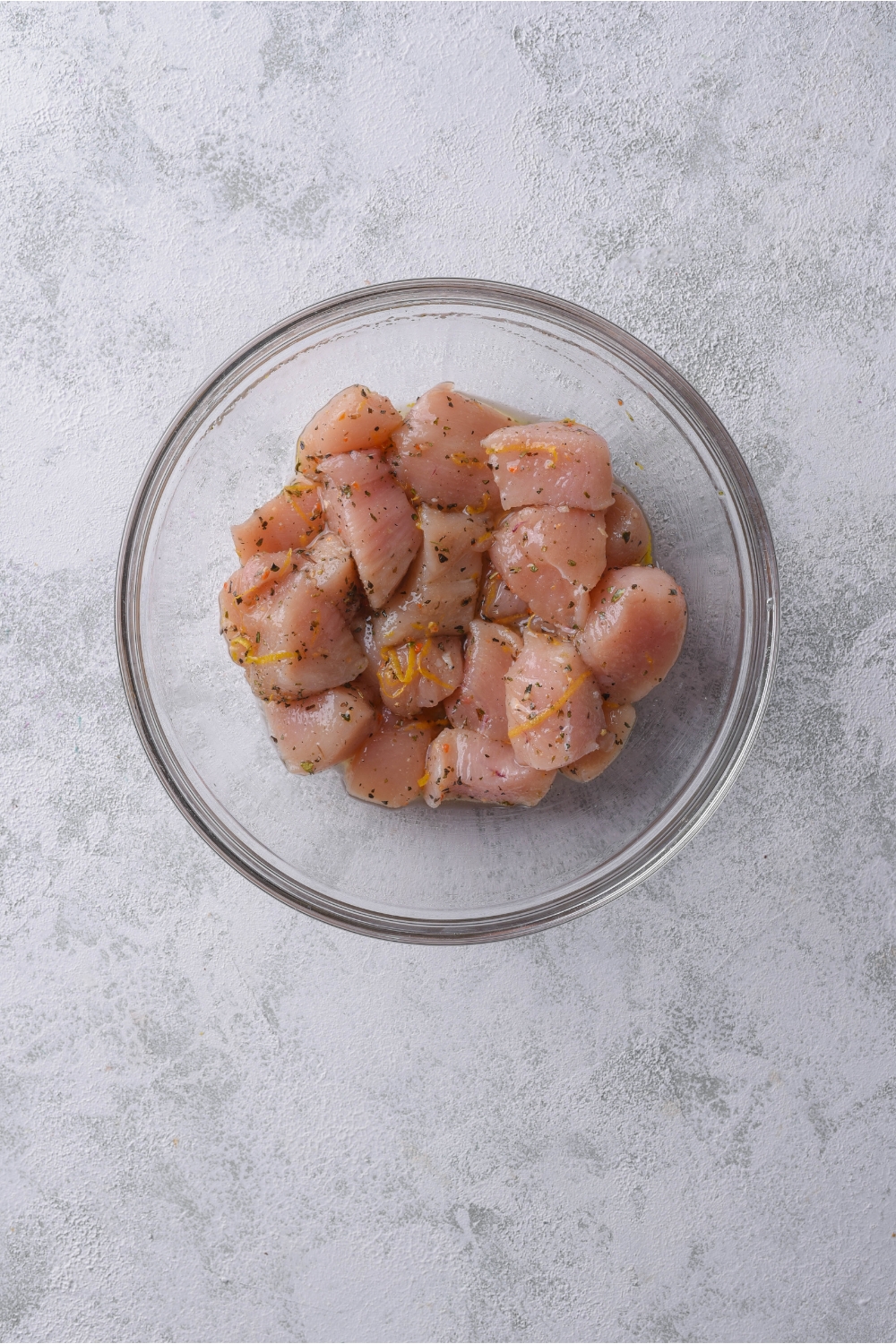 A bowl of raw marinating chicken cut into bite-sized pieces.
