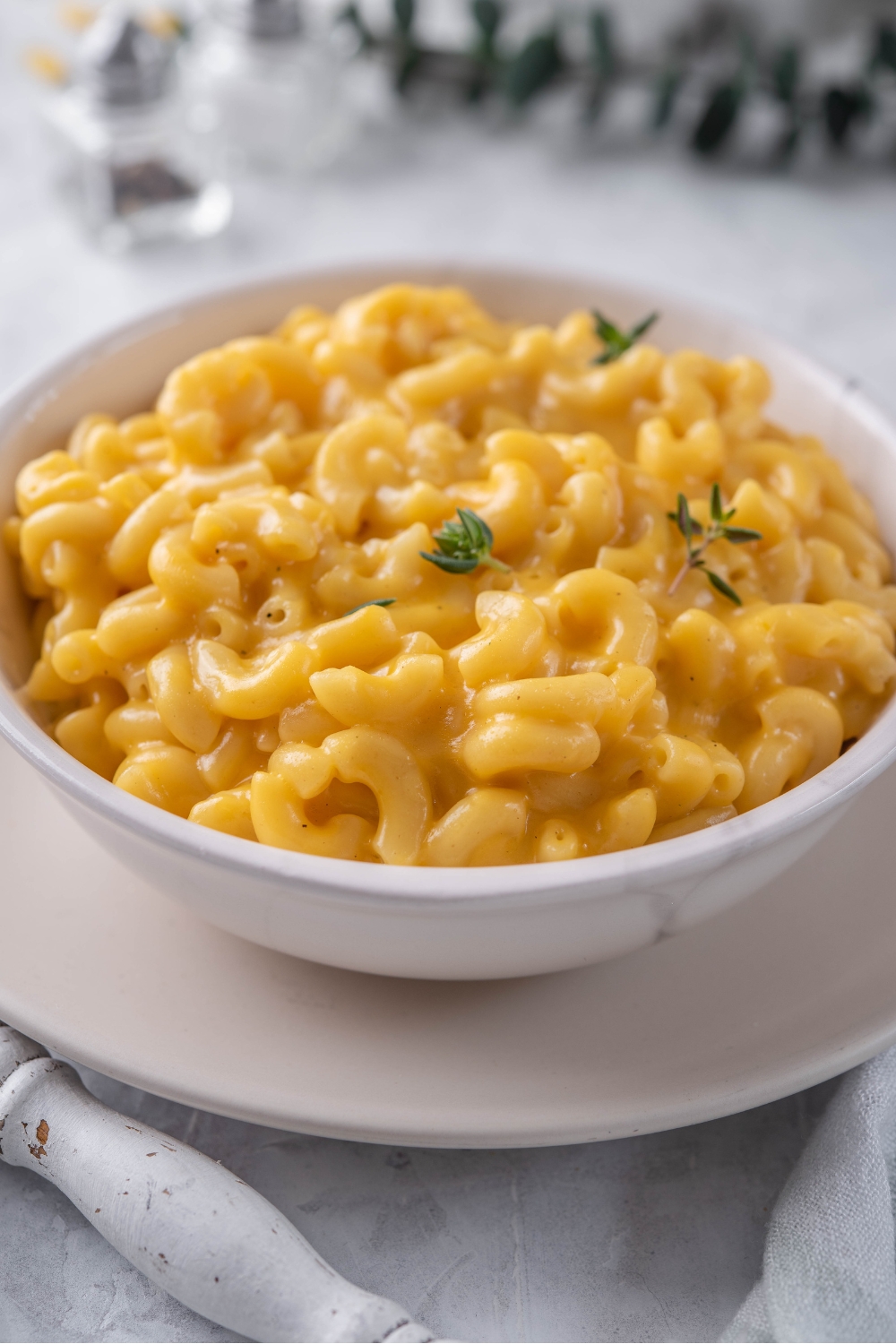 Close up of a bowl of creamy mac and cheese with fresh herbs sprinkled on top.