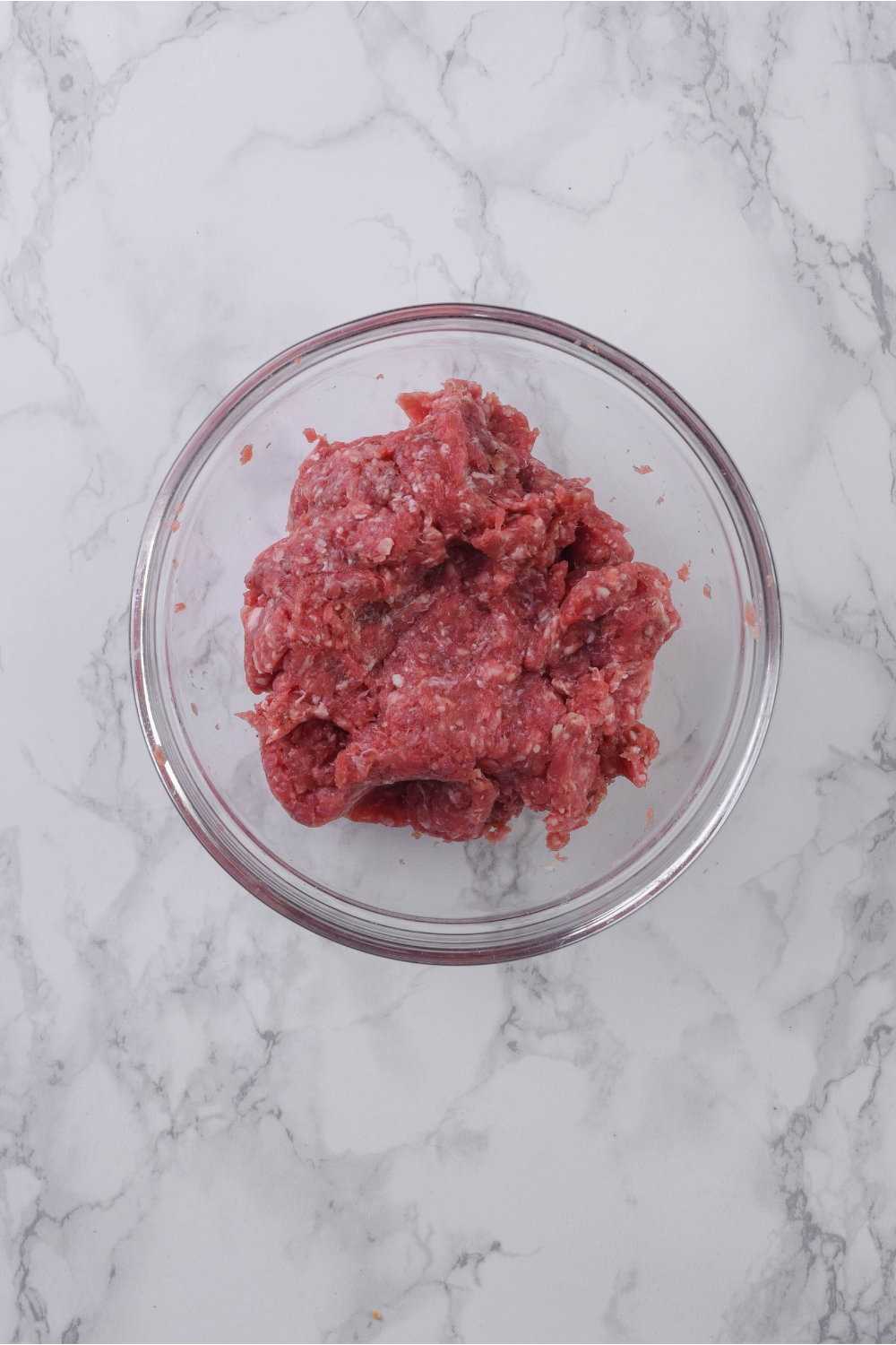 A clear bowl with seasoned ground beef in it.