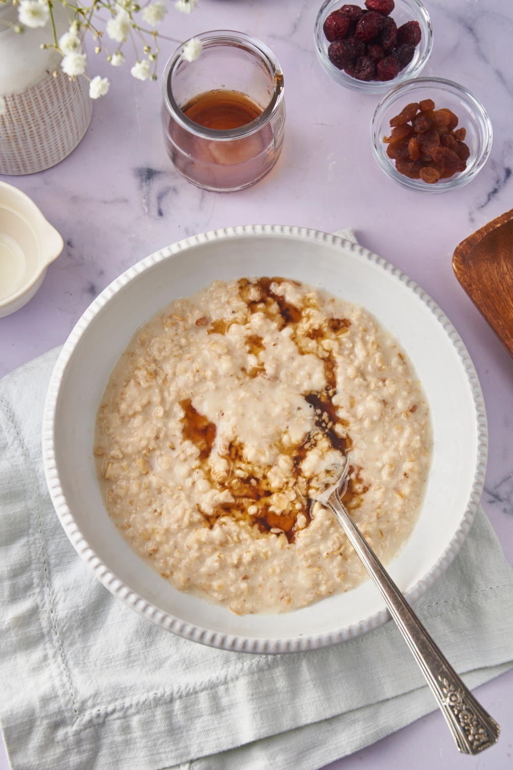 A bowl of creamy oatmeal with maple syrup drizzled on top of it.