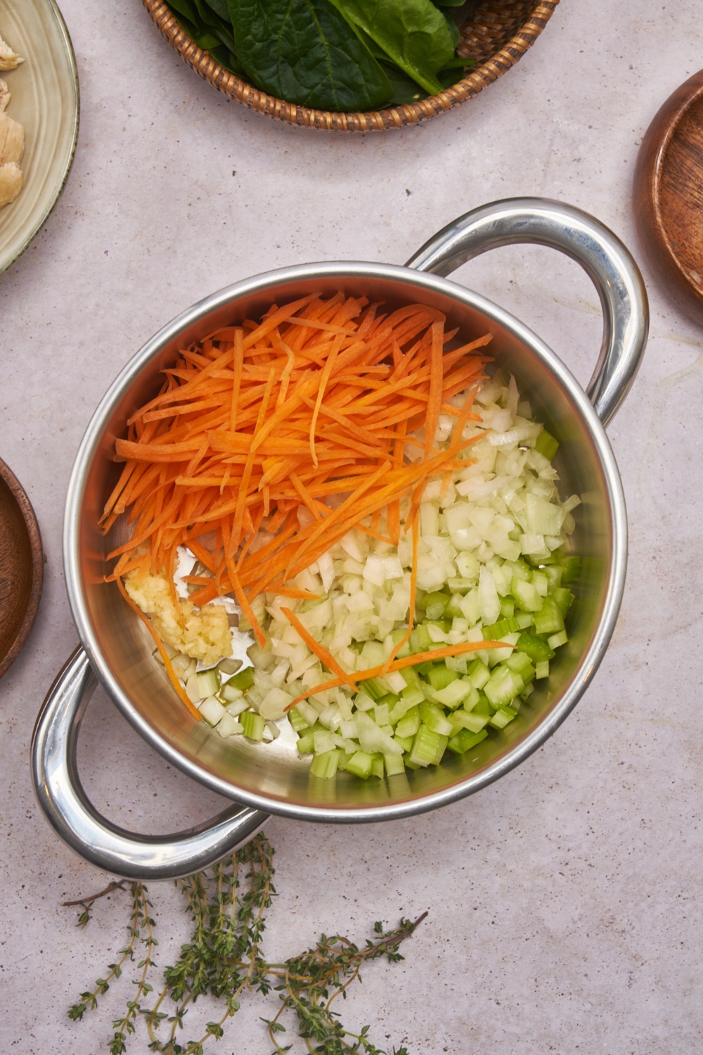 A large pot filled with diced celery, onion, minced garlic, and shredded carrots.