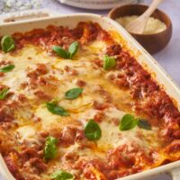 Baked lasagna covered in melted cheese and garnished with fresh basil.