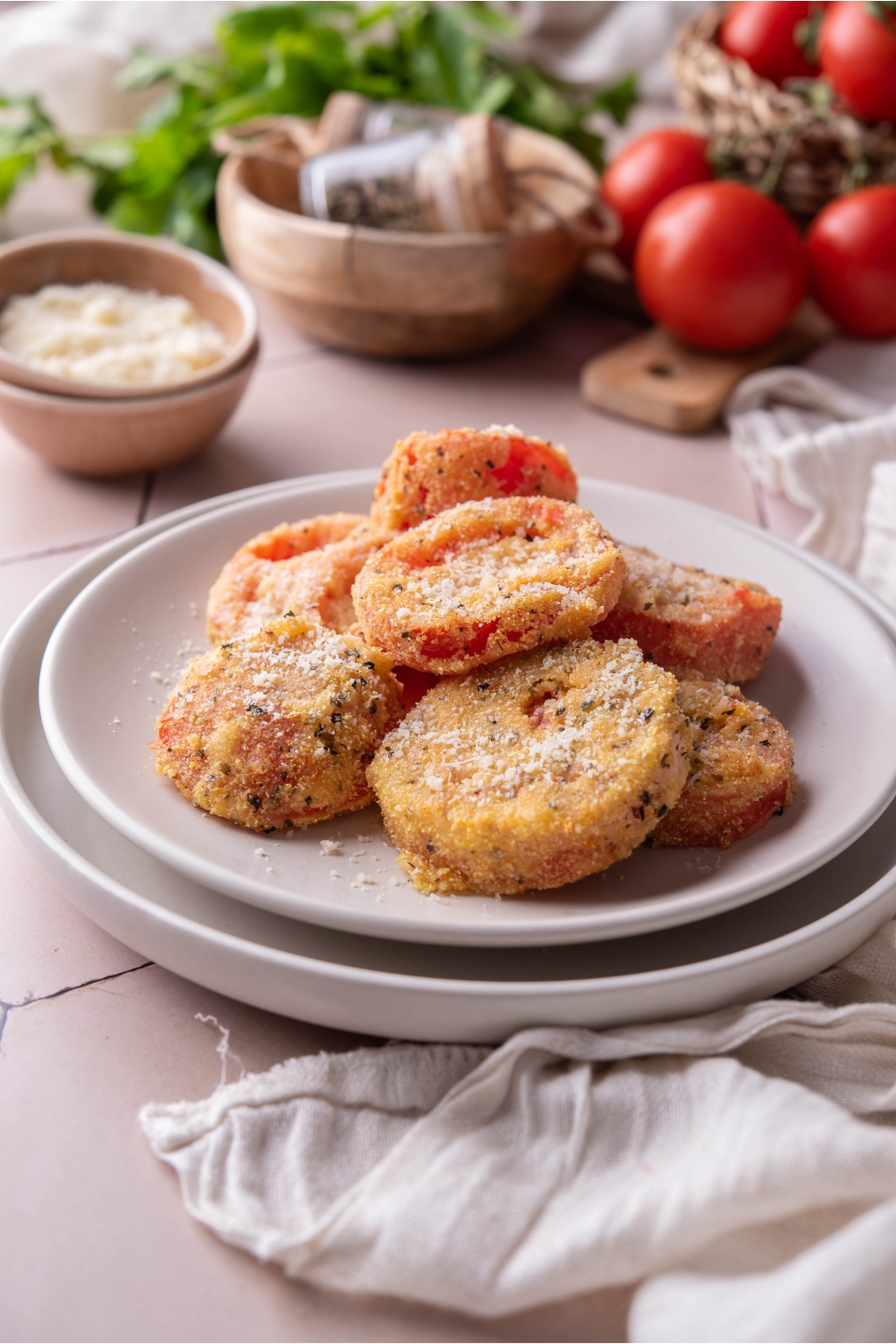 A pile of fried red tomatoes on a white plate with a second plate beneath it.