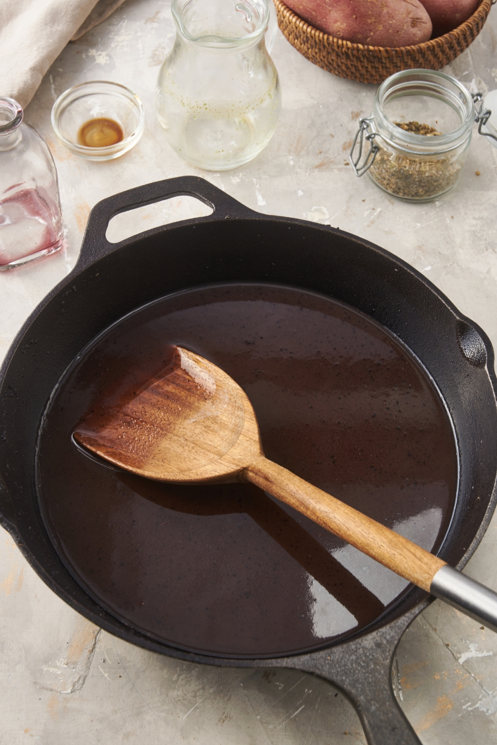 A cast iron skillet with brown gravy and a wooden spoon in it.