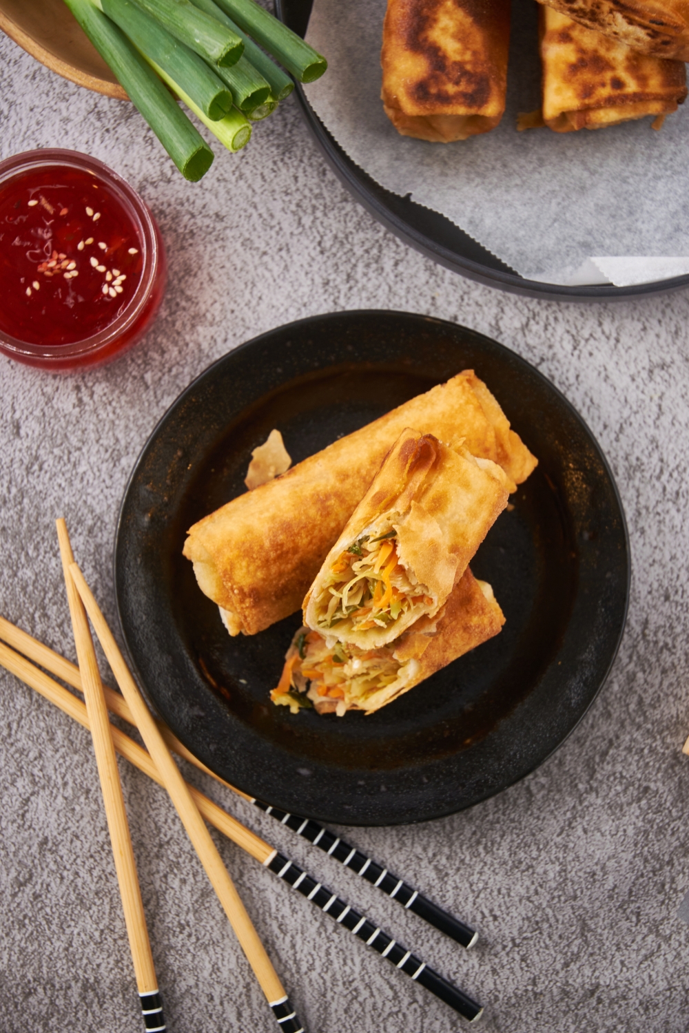 Overhead view of two fried egg rolls with one sliced in half and stacked on top of each other.